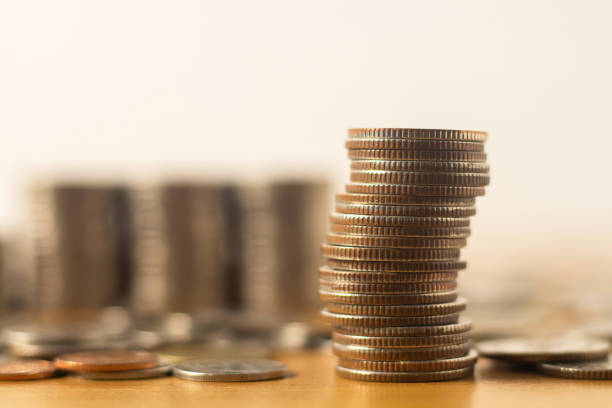 istock Silver coins stacked high on a wooden table 1431397023