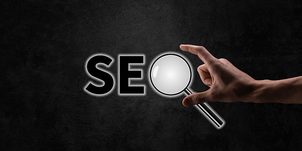 SEO Search Engine Optimization, Woman holding through magnifying glass with text SEO, concept for promoting ranking traffic on website, optimizing your website to rank in search engines.