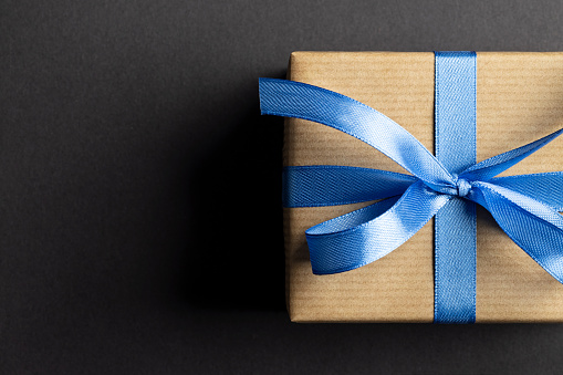 Gift box with blue ribbon on black. This file is cleaned and retouched.