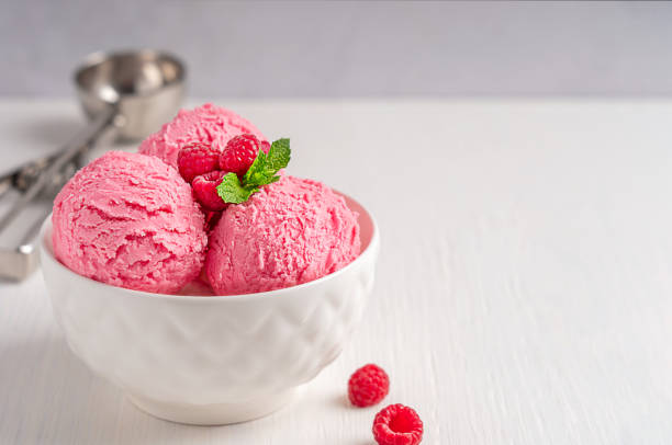istock Bowl with refreshing sweet berry pink ice cream scoops with raspberries and mint leaf on white wooden table 1431411189
