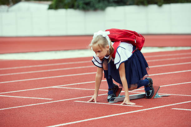 Young girl running on the running track at the stadium outdoors