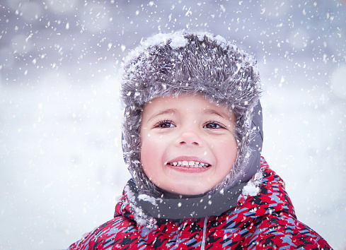 Happy child having fun, enjoying winter snowy day. Portrait of three years old cute smiling trendy hipster boy (kid) in winter wear (clothes). Caucasian kid playing outside. Winter, healthy lifestyle, Christmas, travel concept. Selected focus.