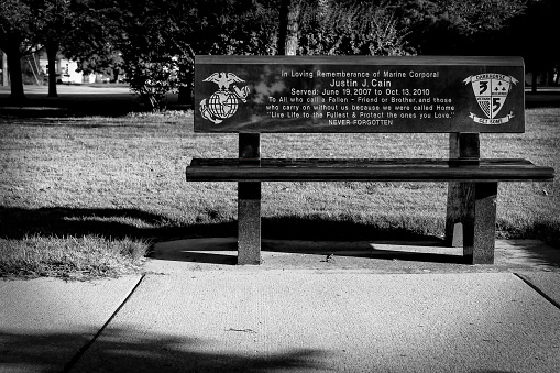 Manitowoc, Wisconsin, USA - July 25, 2022: A memorial bench dedicated to Marine Corporal Justin Caine at the Manitowoc County Veterans Memorial Park.