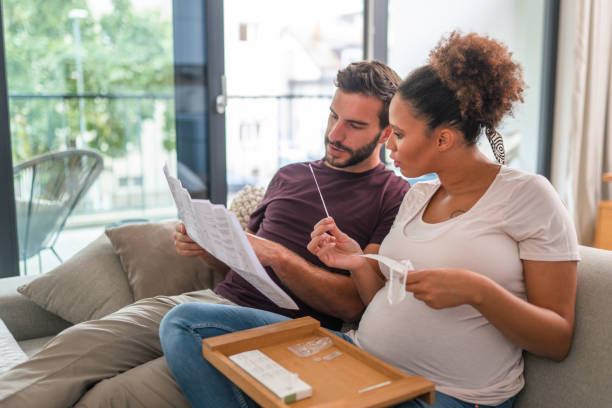 istock Heterosexual Couple Sitting On The Sofa And Reading Instructions For Covid Self Test 1431421920