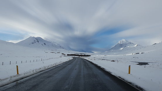 Empty road leading to snow covered mountains