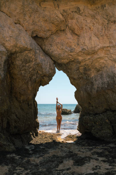 istock Woman in bikini standing between rocks on seashore 1431425309