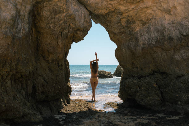 istock Woman in bikini standing between rocks on seashore 1431425314