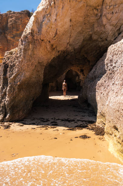istock Carefree woman standing in cave on sandy beach 1431425323