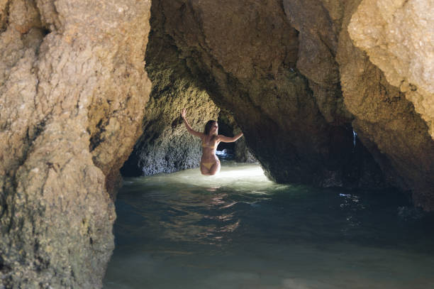 istock Woman walking through seawater in rocky cave 1431425335