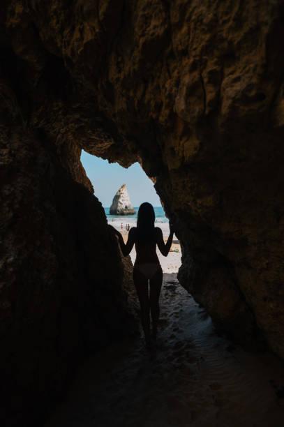 istock Woman admiring seashore from cave in summer 1431425348