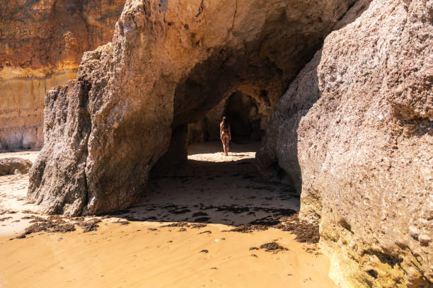 istock Carefree woman standing in cave on sandy beach 1431425367