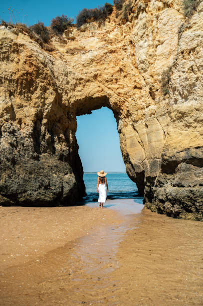 istock Unrecognizable woman walking on beach with rock 1431427428