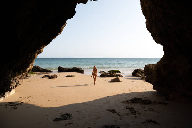 istock Lady in bikini strolling on sandy seacoast near cliffs 1431427464
