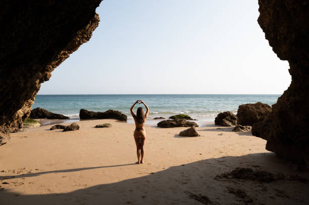 istock Lady in bikini showing heart gesture on sandy beach 1431427467
