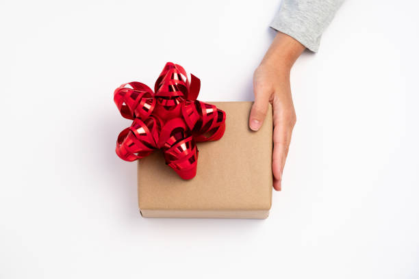 Person giving christmas gift with a red ribbon stock photo