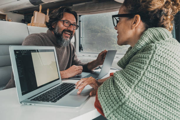 istock Digital nomad young couple working together inside a camper van using laptop computer. Happy free modern people man and woman in smart working travel activity. Online job and technology connection 1431429134