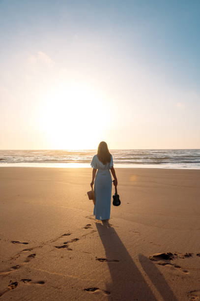 istock Anonymous woman with ukulele standing on beach 1431429803