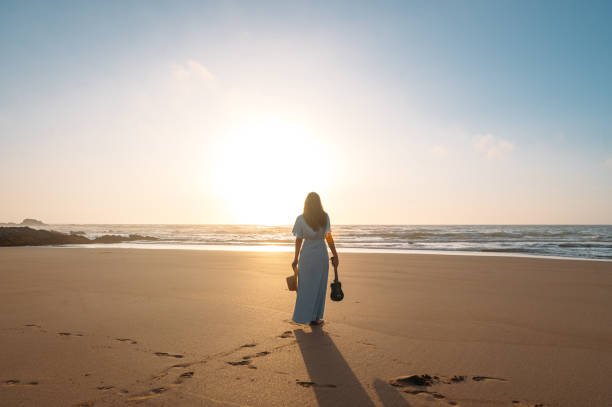 istock Anonymous woman with ukulele standing on beach 1431429812