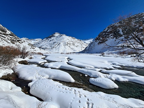 Mountain range of the French Alps. Bonneval sur Arc in winter.  The mountain is covered with snow. Small stream. Footprints on the snow.