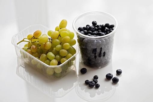 fruits in plastic containers: grapes and blueberries