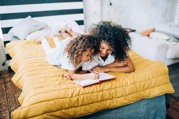 istock Black mother and daughter lying on bed and doing homework together 1431432979