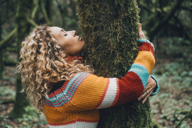 Side view of woman hugging a tree with green musk in love. Concept of people and environment. Outdoors leisure activity female in forest woods. Nature protection agains climate change and global warm stock photo