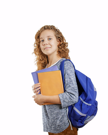 pretty girl with curly hair teenage  with a backpack and books isolated on a white background