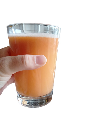 a person holds a glass of fresh carrot, apple and pear juice