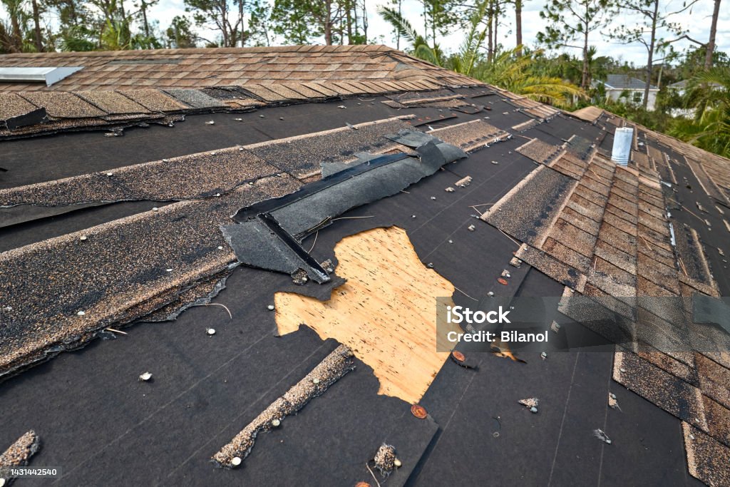 Damaged house roof with missing shingles after hurricane Ian in Florida. Consequences of natural disaster Damaged house roof with missing shingles after hurricane Ian in Florida. Consequences of natural disaster. Rooftop Stock Photo