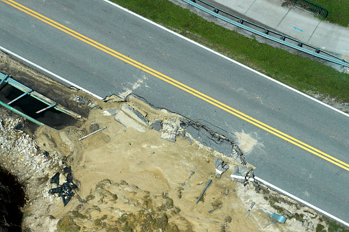 Aerial view of damaged road after flood water washed away asphalt. Rebuilding of ruined transportation infrastructure.