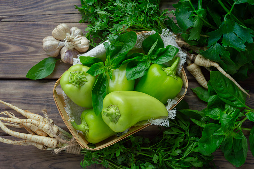 Fresh sweet peppers and herbs on a wooden table. View from above. Flat lay. Healthy food and lifestyle concept. Gardening. Parsley, dill, basil, celery, onion, tomato and celery. Salad. Summer, autumn