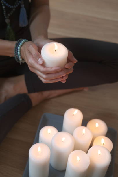 istock Women's hands light candles with matches. Yoga practice and fire in the palms 1431448478