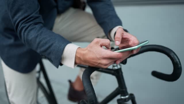 Man typing on mobile while sitting on a bicycle