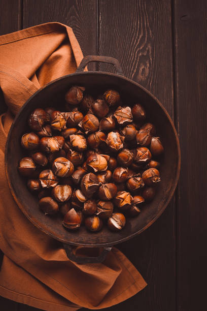 istock Roasted chestnuts, in an iron pan, wooden table, top view, no people, rustic style, 1431459056