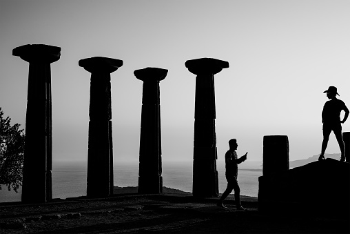 Canakkale, Turkey - August 4 2021: Temple of Athena in Assos with silhouette of woman and man. Black and white photograph.