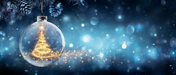 Photo of Christmas Tree In Snow Ball Hanging Fir Branch With Golden Glittering On Blue Abstract Night