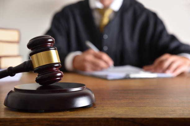 detail of gavel and judge signing on desk in background - contract signing document legal system imagens e fotografias de stock