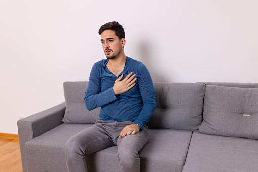 Sad afraid mid adult Caucasian man holding a hand on his chest, having a fear of a heart attack