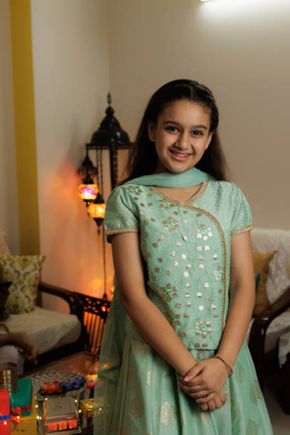 Young girl, kid, dressed up in ethnic wear standing with smile expression pose for photo celebrating diwali Hindu festival Laxmi poojan stock photo