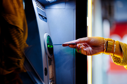 An anonymous businesswoman inserting credit card to cash machine.