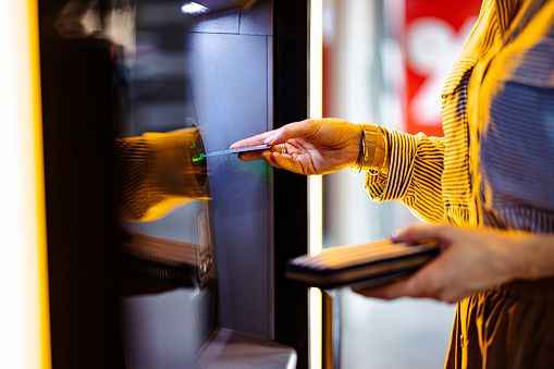 An anonymous businesswoman withdrawing money from cash machine.