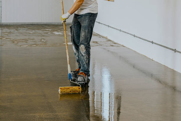 istock Worker, coating floor with self-leveling epoxy resin in industrial workshop. 1431478675