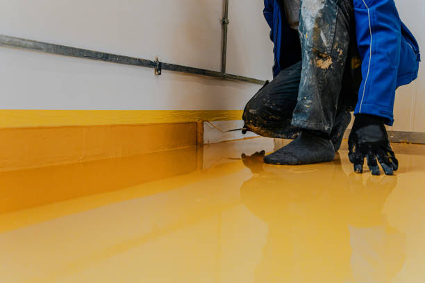 istock Worker, coating floor with self-leveling epoxy resin in industrial workshop. 1431479712
