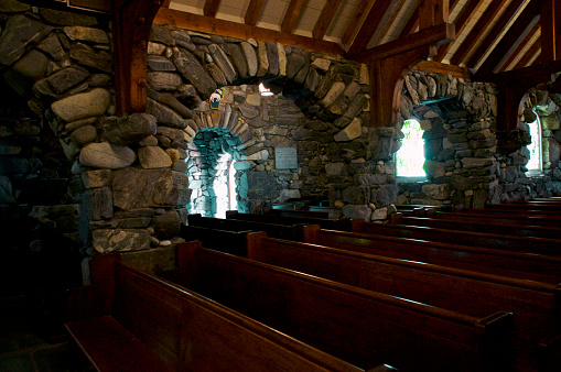 The beautiful church, St. Anns Stone Chapel in kennybunkport maine, showing rows of wooden pews and sone arch entrances.