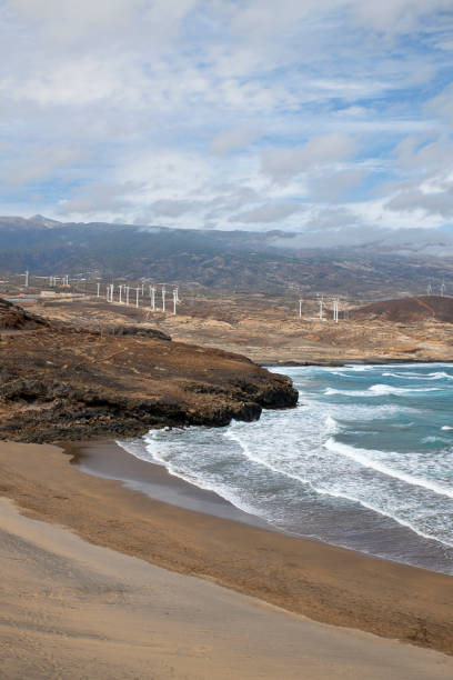 elevated views of the empty beach and the spectacular volcanic coast with scattered wind turbines - image alternative energy canary islands color image imagens e fotografias de stock