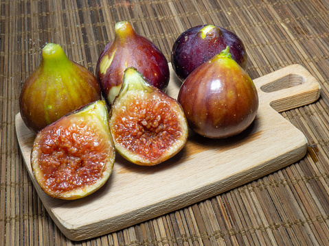 Juicy ripe figs on a cutting board. Halves of figs. Southern fruits on the table. Sliced purple fruits.Pulp of figs on the board in the kitchen.