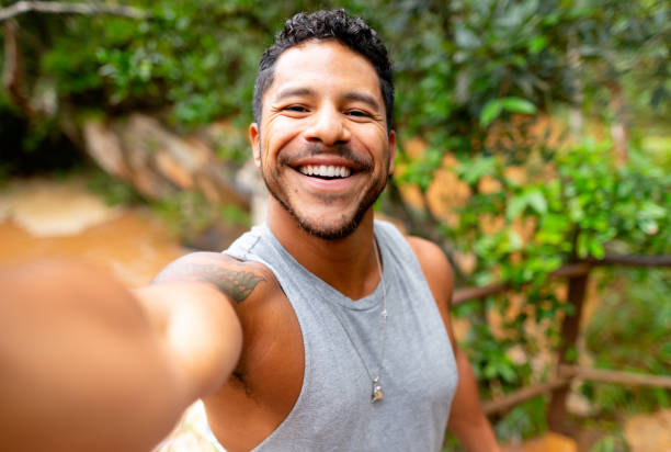 istock Young man smiling and taking selfies overlooking a tropical river 1431500730
