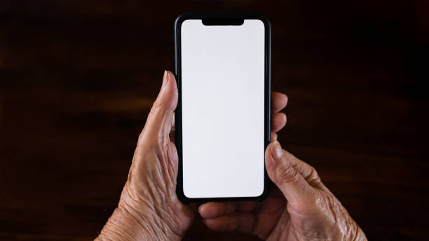 istock Old woman at home using a mobile phone with white screen. Mockup device 1431504260