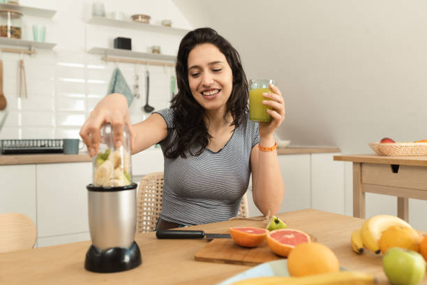 istock Happy young woman making a smoothie for refreshment 1431512649