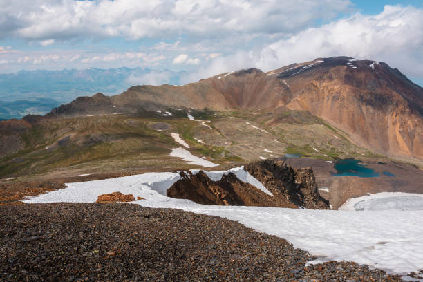 istock Dramatic mountain landscape with colorful mountain valley and low clouds on mountains in changeable weather. Awesome scenery with rocks and lake in mountain valley. Sunny and cloudy scenic alpine view 1431512702
